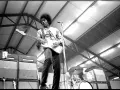 Jimi Hendrix, icône du jimi hendrix style de musique, électrise la scène avec sa guitare blanche. Amplis Marshall et batterie en arrière-plan.