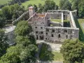 Ruiny zamku w Ząbkowicach Śląskich, z charakterystyczną basztą i murami obronnymi, otoczone zielenią.