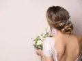 Eleganckie wesele: wlosy podpiete z jednej strony, ozdobione perłami, z bukietem kwiatów w dłoni.