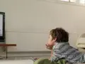 Chłopiec leży na dywanie przed telewizorem, oglądając bajkę. Trzyma pilota, gotowy do zmiany kanału.
