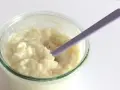 Budino cremoso, profumato alla vaniglia, come quello della ricetta della nonna, pronto per essere gustato con un cucchiaino viola.