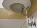 Dettaglio del fondo di uno scaldabagno con tubi flessibili e valvola di sicurezza. Guida su come regolare valvola di sicurezza scaldabagno.