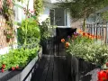 Un vibrante huerto urbano en un balcón, con girasoles, flores coloridas y plantas verdes en macetas.