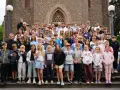 Große Gruppe von Kindern und Jugendlichen vor einer Kirche, die an einem christlichen Ferienlager teilnehmen.
