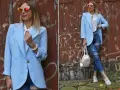 Kobieta w błękitnej marynarce i podartych jeansach prezentuje stylowe stylizacje. Okulary przeciwsłoneczne dodają charakteru.
