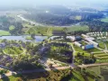 Widok z lotu ptaka na Folwark Łochów, z malowniczymi stawami, budynkami i rzeką w tle.