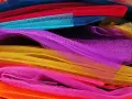 Un tas de **tulle** aux couleurs vives : orange, rose, jaune, violet, bleu et rouge.