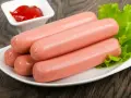 Kilka parówek na talerzu z sałatą i ketchupem. Idealne do szybkiego obiadu, dowiedz się, jak ugotować parówki.