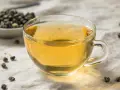 Zaparzona herbata oolong w szklance, obok miseczka z suszonymi liśćmi. Odkryj niezwykłe herbata oolong właściwości.