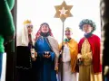 Vier Kinder als Sternsinger evangelisch verkleidet, mit Stern und Spendenbüchse, stehen vor einer Tür.