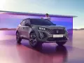 Mężczyzna opiera się o maskę nowego Peugeot E-2008, stylowego peugeot suv, na tle futurystycznej architektury i pustynnego krajobrazu.