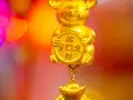 Złoty, uśmiechnięty chiński znak zodiaku szczur trzyma monetę z chińskimi znakami.