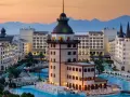 Luksusowy hotel z basenami i wieżą, idealny na wakacje all inclusive w Turcji. Góry w tle.