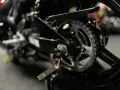Zbliżenie na tylne koło motocykla, widoczny napęd i łańcuch, gotowy do czyszczenia łańcucha motocyklowego.