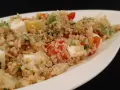 Salade colorée de quinoa avec des dés de feta, avocat, tomates et persil, servie dans un plat blanc.