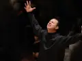 Augusto Biascica, con le braccia alzate e gli occhi chiusi, esprime passione sul palco.