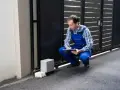 Technicien vérifiant le passage de gaine pour portail coulissant. Il note des informations sur un bloc-notes.
