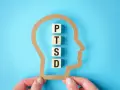 W głowie z papieru litery P, T, S, D układają się w słowo PTSD, symbolizując jego objawy.