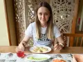 Kobieta przy stole z pierogami i surówką. Posiłek to świetny sposób, jak szybko uzupełnić białko w organizmie.
