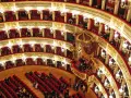 Elegancka loża w teatrze, z czerwonymi aksamitnymi siedzeniami i złotymi zdobieniami, czeka na widzów.