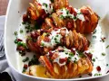 Pyszny obiad z ziemniaków: pieczone ziemniaki Hasselback z chrupiącym boczkiem, śmietaną i szczypiorkiem.