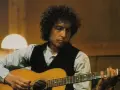 Bob Dylan gra na gitarze, tworząc swoje legendarne utwory.