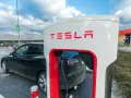 Czarna Tesla podłączona do ładowarki Supercharger.