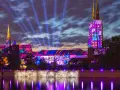 Ostrów Tumski we Wrocławiu nocą, rozświetlony kolorowymi projekcjami i niebieskimi snopami światła.