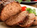 Soczysta, rumiana pieczeń rzymska, pokrojona w plastry, z pomidorkami i bazylią. To najlepsza pieczeń rzymska, jaką można sobie wymarzyć!