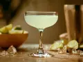 Orzeźwiający daiquiri, idealny na upalne dni. W tle miska z limonkami i kostki lodu.