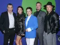Pięcioosobowa detektywi obsada pozuje do zdjęcia. W centrum kobieta w niebieskiej marynarce, po jej bokach aktorzy w eleganckich strojach i skórzanych kurtkach.