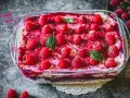 Himbeer Tiramisu in einer Glasform, garniert mit frischen Himbeeren und Minzblättern. Ein köstlicher Nachtisch.