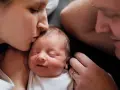 Mutter küsst ihr Neugeborenes, Vater schaut liebevoll zu. Diese Momente sind unbezahlbar, auch nach 1000 Tagen.