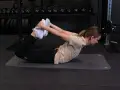 Kvinna på gymmatta gör en bågsträckning för att stretcha magen.