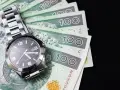 Zegarek na stosie banknotów 100 zł. Czas to pieniądz, a ten schemat zachowań kompulsywnych pokazuje, jak łatwo można stracić kontrolę nad finansami.
