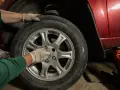 Ręce w rękawiczkach przykręcają śruby koła. Zastanawiasz się, ile kosztuje wymiana opon z wyważeniem?