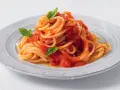 Un piatto di pasta fatta in casa, spaghetti al pomodoro fresco e basilico, serviti su un piatto rustico.
