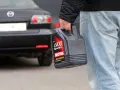 Mężczyzna niesie kanister z olejem silnikowym Motul. W tle czarna Mazda.