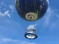 Weltballon über Berlin bei schönem Wetter. Die Gondel mit Passagieren schwebt unter dem riesigen Globus-Ballon.