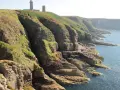 Scogliere verdi e rocciose con un faro in cima. Ideale per consigli su **Bretagna in moto**.