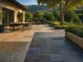 Une belle terrasse en pierre naturelle, avec un coin repas et un salon extérieur, entourée d'un jardin luxuriant.