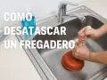 Manos usando un desatascador para desatascar fregadero.