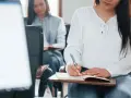 Estudiantes toman notas en clase. Se registran los gastos de formación en la cuenta contable.