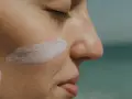 Rostro de mujer con una pincelada de crema solar biodegradable en la mejilla.