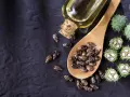 Semi di ricino e olio di ricino spalmato sulla pancia per un rimedio naturale.