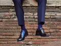 Uomo con calzini blu a pois bianchi e scarpe nere lucide. Un perfetto abbinamento calzini scarpe uomo per un look elegante.