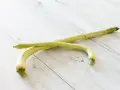 Due zucchine trombetta, perfette per gustose ricette estive, adagiate su un tavolo di legno chiaro.