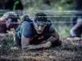 En man kryper under taggtråd under ett ocr sport-lopp.
