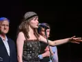 Tatiana Kołodziejska w kwiecistej opasce i ozdobnej sukience śpiewa do mikrofonu, gestykulując ręką.