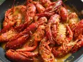Un delicioso cangrejo de río en una sartén, bañado en una cremosa salsa. ¡Un manjar listo para disfrutar!